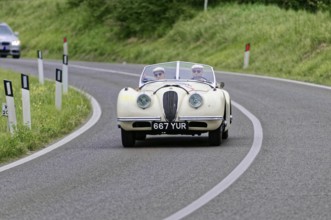 White vintage convertible on a winding country road surrounded by nature, vintage car, car racing,