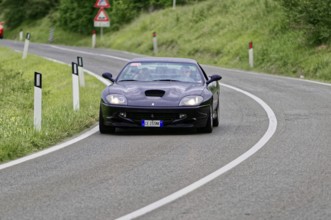 Dark blue sports car on a winding road in a rural setting, classic car, car race, Mille Miglia,