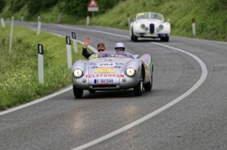 Silver classic car on country road, two people waving from the vehicle, classic car, car race,