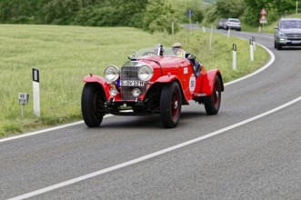 Red vintage car on a country road with green fields and trees, vintage car, car race, Mille Miglia,