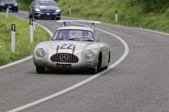 Silver sports car on a winding road surrounded by green landscape, classic car, car race, Mille