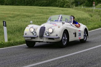 White retro convertible on country road with two people, classic car, car race, Mille Miglia, 1000