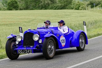 Two people in a blue vintage car on a country road, vintage car, car race, Mille Miglia, 1000