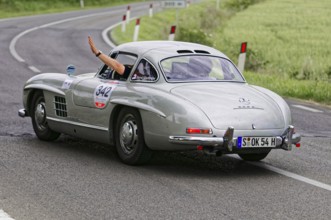 Silver retro sports car turns off on a winding road, classic car, car racing, Mille Miglia, 1000