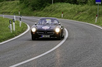 Black classic car drives through a picturesque winding road, classic car, car race, Mille Miglia,