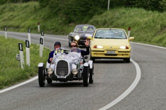Classic racing car with yellow car in the background on country road, classic car, car race, Mille