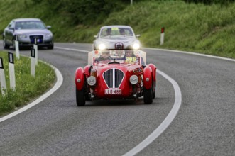 Red classic car on a winding country road at dusk, classic car, car race, Mille Miglia, 1000