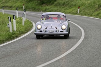Silver classic car on a winding road through green hills, classic car, car race, Mille Miglia, 1000