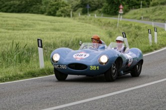Blue racing car with two people on a winding country road, classic car, car race, Mille Miglia,