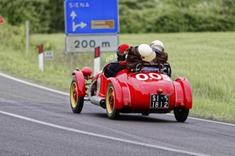 Red classic car on Italian country road towards Siena, classic car, car race, Mille Miglia, 1000