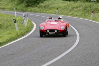A red vintage convertible car with two occupants drives fast on a tarmac road, vintage car, car