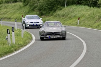 Two classic Mercedes cars driving on a winding country road in a green environment, classic car,