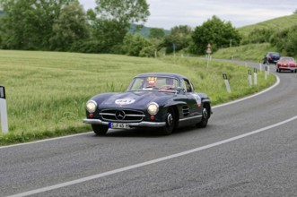 A black Mercedes classic car drives stylishly through the green landscape, classic car, car race,