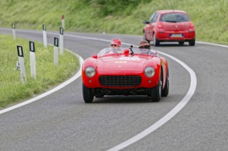 Red Ferrari vintage convertible on a winding country road during a race, vintage car, car race,