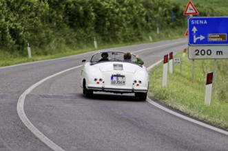 A white vintage convertible on an open country road towards Siena, vintage car, car race, Mille
