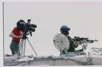 BIH, Tuzla, 01.05.1993 -- A cameraman and a British UN soldier wait for refugees from Srebrenica to