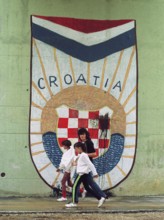 HRV, Split, 01.10.1991 -- Passers-by walk past the Croatian national coat of arms at an underpass