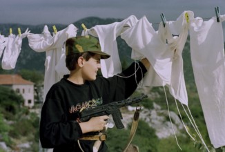 HRV, Kraotien, Dubrovnik 20.09.1993 Child with toy gun behind laundry. HRV Croatia, Dubrovnik, 1993