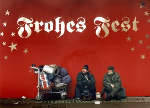 DEU, Frankfurt/Main, 13.12.99 -- Two homeless people are begging under the inscription Frohes Fest.