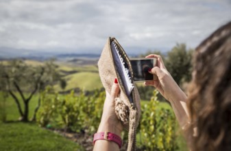 ITA Italy Castelfalfi A woman takes a photo with her smartphone on the hotel terrace