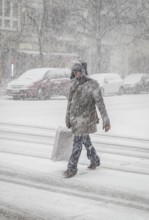 DEU Germany Germany Berlin People in the city during a snow shower.Pedestrian crosses snowy road