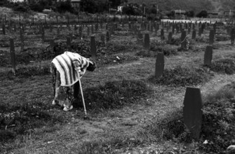 BIH, Bosnia, Screbrenica, 10.07.2005, An old woman leaning over a Muslim grave cross