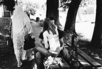 BIH, Bosnia, Tuzla, 11.07.2005, Muslim woman passes by kissing couple