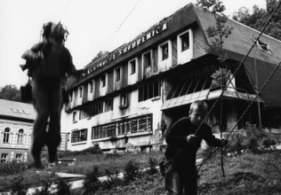BIH, Bosnia, Screbrenica, 10.07.2005, Children swing in front of hotel ruins