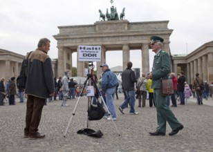 DEU Germany Berlin fundraisers in GDR uniform with a state border sign. The Lord collects donations
