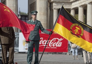 DEU Germany Berlin Actor wearing NVA uniform poses with the GDR flag in front of a Coca-Cola