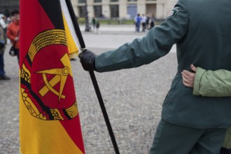 DEU Germany Berlin Actor with GDR flag is hugged by tourists while taking pictures. Scene on the