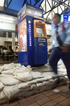 A man in uniform passes by an ATM that has been protected against the floods of Chao Praya with