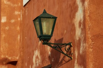 A green lantern hangs on a rust-tinted wall with distinct texture, Monemvasia, Monemvassia,