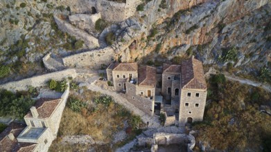 Drone view, aerial view of an ancient fortress with stone houses and vegetation on rocky terrain,