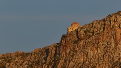 Orhodox church of Hagia Sophia, chapel high on a rock, illuminated in orange evening light,