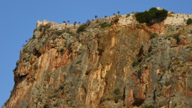 Soft morning light, spectacular cliffs with castle walls and distinct geological layers,