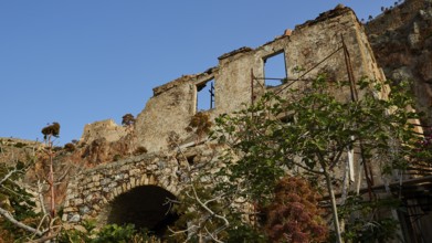 Dilapidated stone structure nestled in lush vegetation under clear skies, Monemvasia, Monemvassia,