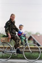 BIH, Bosnia, Tuzla, 23.08.1994 A Bosnian soldier rides a bicycle with his son