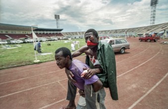 RWA Rwanda Kigali An injured Tutsi refugee who fled to the sports stadium is carried by a man to a