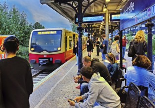 People wait for the incoming S-Bahn at Yorkstraße S-Bahn station in the evening, Berlin, Germany