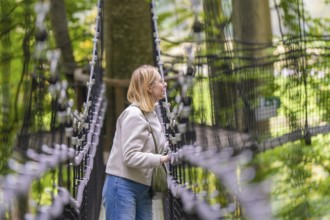 Woman on a rope bridge in the forest, surrounded by trees, Treewalk, Affenberg Salem,