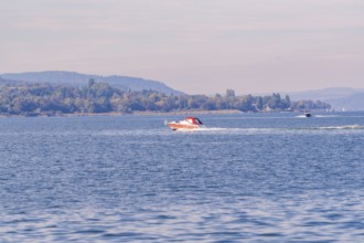 Two motorboats race across the water surface of a lake in a vast landscape, boat trip, Lake