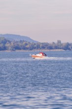 A motorboat sails at high speed across a quiet lake in autumn surroundings, boat trip, Lake
