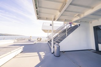 An upper deck of a modern ship with seats and a view of the sea under a blue sky, Schiff Fahrt,