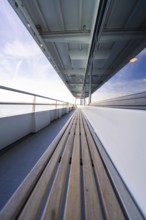 Long ship deck with wooden bench, looking out to sea, with a clear sky above, boat trip, Lake