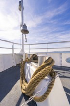 A ship deck with thick ropes and a bell, in front of a clear blue sky at sea, boat trip, Lake