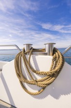Thick ropes carefully draped on the boat deck in front of a wide sky and sea view, boat trip, Lake
