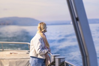 Woman looking relaxed from the ship at the calm water under a blue sky, Schiff Fahrt, Lake