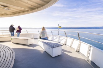 Passengers enjoy the view from a ferry in clear weather, Schiff Fahrt, Lake Constance, Germany
