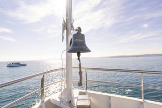 Ship bell aboard a boat on a calm sea under sunny sky, boat trip, Lake Constance, Germany